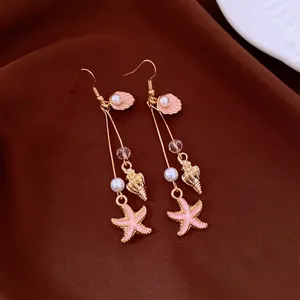 Close-up of bohemian starfish and seashell drop earrings with pink pearls and crystals