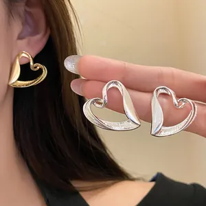 Close-up macro view of exaggerated gold and silver heart earrings with textured finish