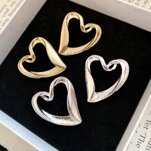Close-up of gold and silver heart-shaped stud earrings in a luxury display box