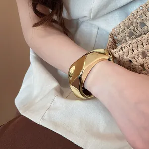 Dettaglio ravvicinato di un bracciale rigido largo in resina dorata irregolare