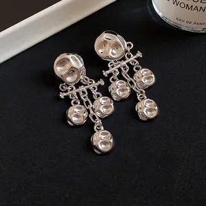 Detail of silver metal pleated earrings with irregular tassel drops