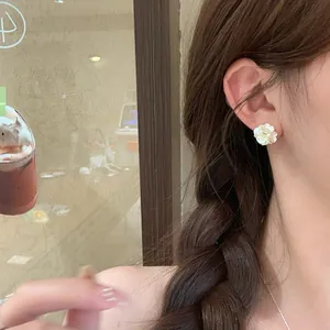 Close-up of elegant pearl flower stud earrings worn on an ear for a sweet look