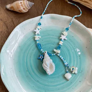 Summer vacation style beaded necklace with conch and starfish pendants on blue plate