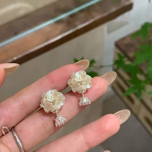 Detailed view of elegant flower ball stud earrings with zircon drops held in hand