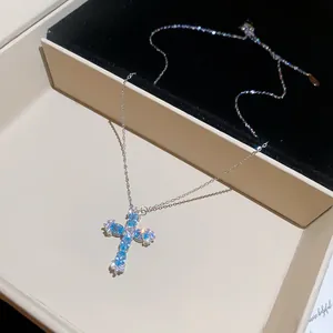 Detailansicht einer silbernen Kreuzhalskette mit funkelnden hellblauen Edelsteinen.