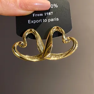 Close-up detail of vintage gold-plated double heart stud earrings with a shiny metallic finish.