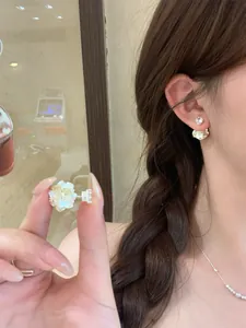 Close-up detail of dainty zircon pearl flower stud earrings worn by an elegant model.