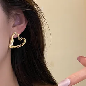 Close-up of a large gold open heart-shaped earring worn on a model's ear