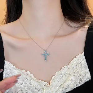 Elegante Silberkette mit einem hellblauen Zirkon-Kreuzanhänger, getragen von einem Model