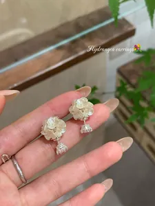 Macro view of elegant hydrangea earrings featuring white pearl petals and zircons