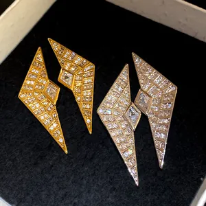 Detail view of geometric zircon stud earrings in gold and silver finishes