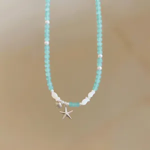 Close-up detail of a blue beaded necklace with silver starfish and shell charms.