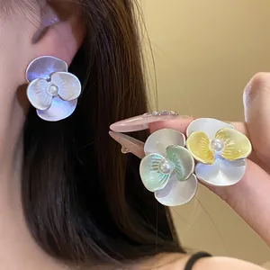 Detailed close-up of matte orchid flower stud earrings with pearl centers in multiple colors