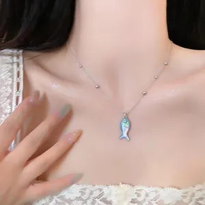 Elegant close-up of a silver beaded chain necklace with an iridescent blue fish pendant.