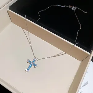 Detailansicht eines silbernen Kreuzanhängers mit blauen Zirkonen in einer Schmuckschatulle.