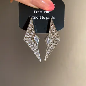 Detailed view of geometric silver needle earrings with shimmering zircon inlays
