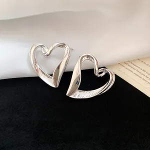 Detailed macro shot of vintage oversized silver heart stud earrings with metallic texture