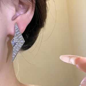 Detail view of geometric silver stud earring with sparkling zircons on model ear