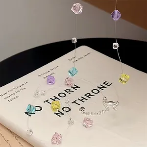 Dettaglio di una collana di perle di cristallo colorato su un libro bianco.