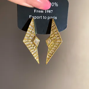 Close-up of geometric gold rhombus earrings with sparkling cubic zirconia stones