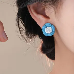 Eleganti orecchini a lobo a fiore blu estivo con perla centrale su modella