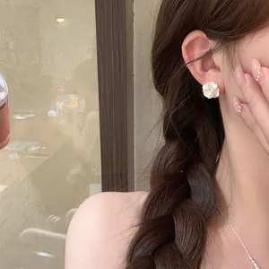 Close-up detail of a delicate white pearl flower stud earring on a female ear