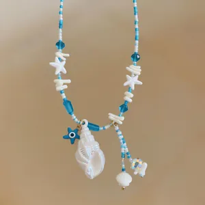 Detailed macro of a summer beaded necklace featuring a white shell and blue evil eye charm