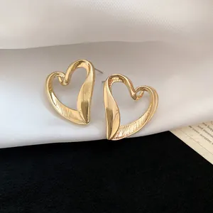 Close-up of vintage gold heart stud earrings with brushed metallic texture