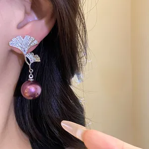 Macro detail of elegant ginkgo leaf drop earrings with purple pearl and pavé stones