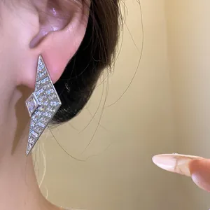 Detailed view of geometric silver stud earrings with sparkling zircon crystals