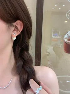 Close-up view of elegant zircon and pearl flower stud earrings worn by an Asian model