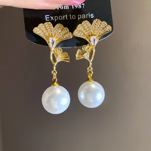 Close-up of elegant 18K gold plated ginkgo leaf earrings with sparkling zircons and pearls
