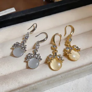 Dettaglio di orecchini in stile francese con fiocchi di strass e pietre tonde in resina