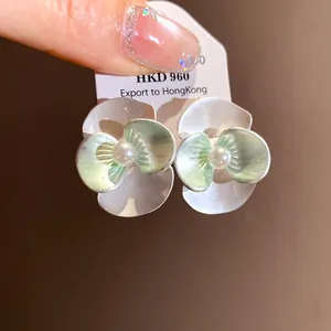 Close-up detail of elegant pearl flower earrings with light green enamel finish