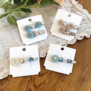 Elegant rhinestone and resin flower hair clips in blue and beige tones on cards.