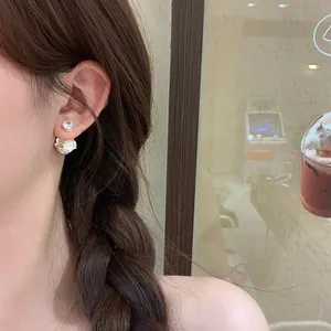 Detailed side view of sweet zircon flower earrings worn by a model in a café setting