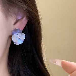 Detailed view of elegant silver needle flower stud earrings with a central pearl on model's ear.