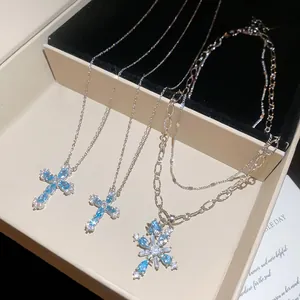 Detailansicht von Silberhalsketten mit blauen Zirkon-Kreuz- und Schneeflockenanhängern.