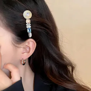 Detail view of a luxury floral resin hair clip with blue gemstone set on dark wavy hair