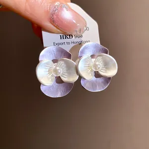 Macro view showing the detailed enamel petals and central pearl of these flower earrings.
