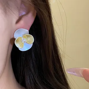 Elegant flower stud earrings with yellow drip oil petals and pearl center worn on ear