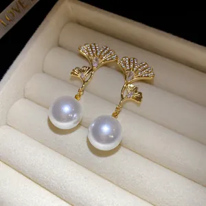 Macro view of gold-plated ginkgo leaf earrings with zircon and drop pearls