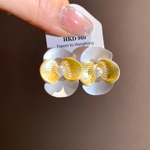 Close-up of pearl flower earrings featuring gold and silver textured petals