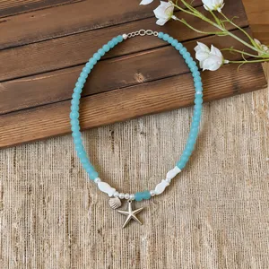 Detail view of summer starfish and seashell charms on blue beaded necklace chain