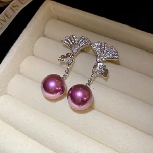 Detailed view of elegant silver ginkgo leaf earrings with zircons and purple pearls