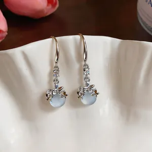 Dettaglio di orecchini a gancio in resina con strass in stile francese su un piatto.
