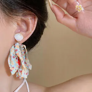 Close-up of beach style shell earring with colorful polka dot chiffon tassels