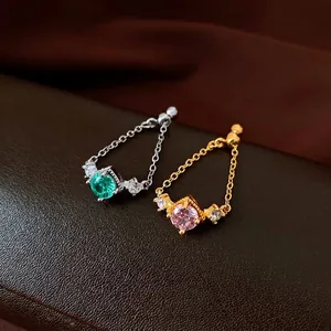 Elegant retro chain rings with green and pink zircon stones on leather background.