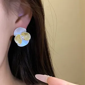 Close-up of elegant flower stud earrings with yellow enamel petals and pearl center