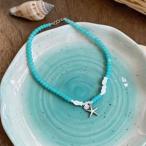 Macro view of silver starfish and seashell charms on a fresh turquoise beaded necklace.